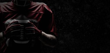 Eski yıpranmış duvara ragbi topu tutan Amerikan futbolu oyuncusu