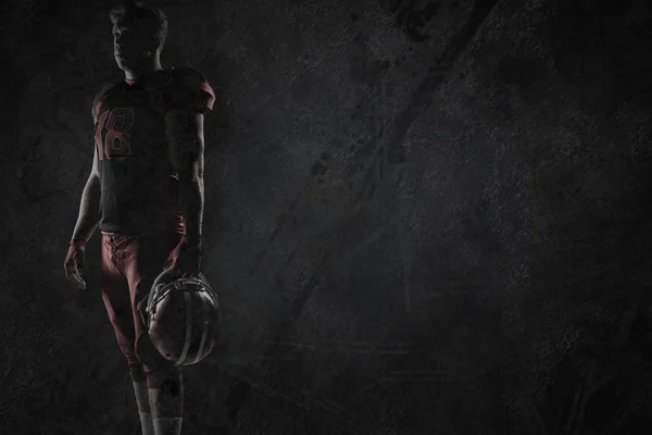 在深灰色背景下拿着橄榄球头盔的排球运动员 — 图库照片