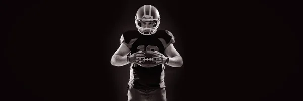 戴头盔拿着橄榄球的年轻美国足球运动员 — 图库照片
