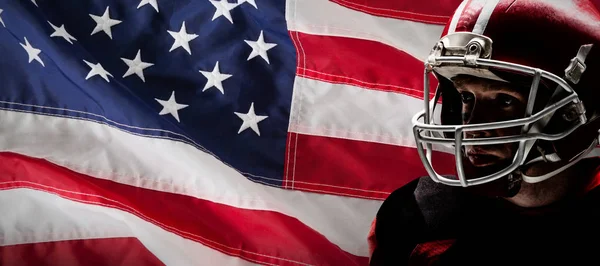 アメリカの国旗のクローズ アップに対するラグビー ヘルメットに立っているアメリカン フットボール プレーヤー — ストック写真