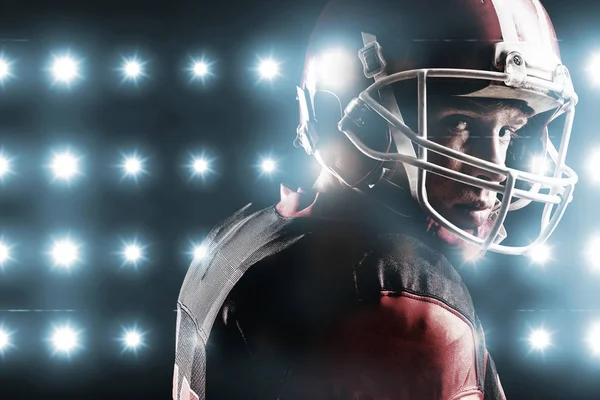 デジタル ヘルメット黒の背景に立ち向かうアメリカン フットボール選手に対してブルー スポット ライトのイメージを生成 — ストック写真