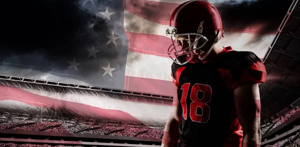 アメリカの国旗のクローズ アップに対するヘルメットに立っているアメリカン フットボール プレーヤー — ストック写真
