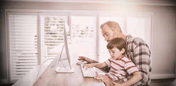 Father and son working on computer at home