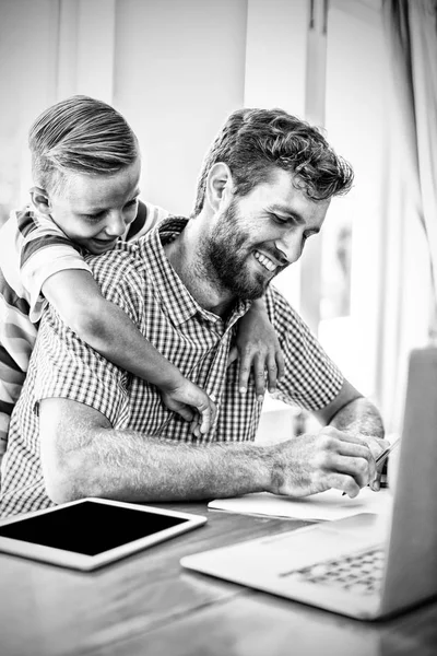 Sorrindo Filho Apoiando Pai Trabalhando Com Laptop Tablet Casa — Fotografia de Stock