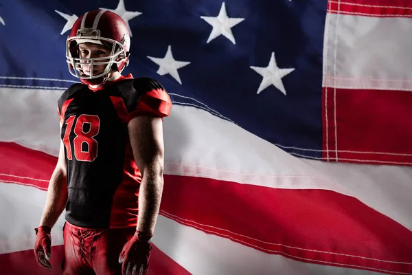 アメリカの国旗のクローズ アップに対するラグビー ヘルメットと立っているアメリカン フットボール プレーヤー — ストック写真