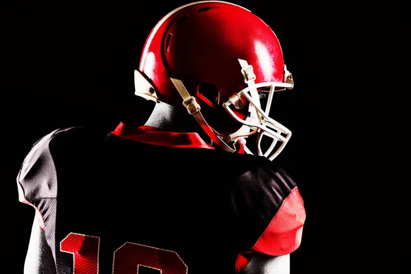 側を見つめているヘルメットでアメリカン フットボール プレーヤーの背面図 — ストック写真