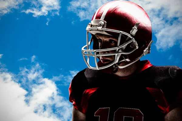 美国足球运动员戴着头盔站在美丽的天空和云朵的视线 — 图库照片