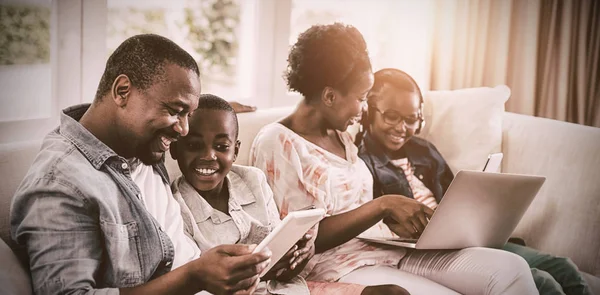 Hymyilevät Vanhemmat Lapset Käyttävät Kannettavaa Tietokonetta Digitaalista Tablettia Sohvalla Kotona — kuvapankkivalokuva