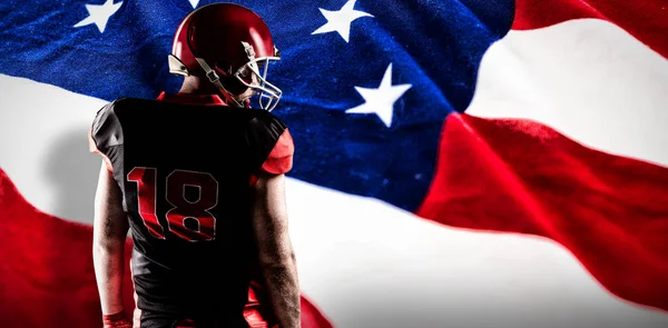 星条旗アメリカの国旗に対するラグビー ヘルメットに立っているアメリカン フットボール プレーヤー — ストック写真