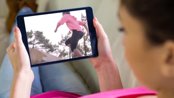 デジタル タブレットを祝う女性のスポーツ ビデオを見てソファの上に座っている女性 — ストック動画