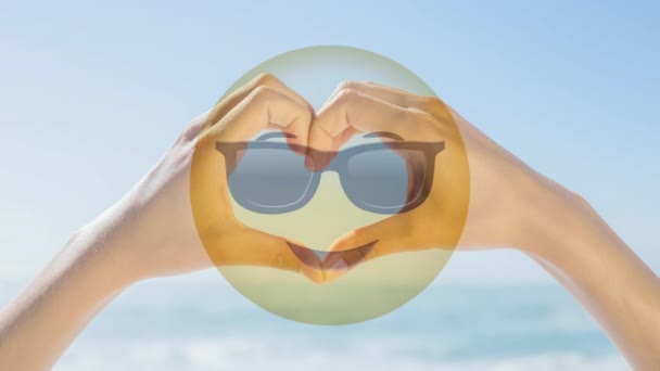 动画太阳镜微笑对心脏形状与手和海在阳光背景下 — 图库视频影像