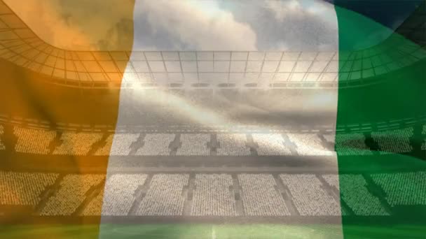 晴れた日にサッカー スタジアム背景風になびかせてコートジボワール フラグ — ストック動画