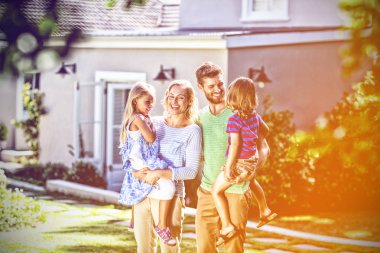 Karşı evin bahçesinde çocuk taşıyan anne gülümseyerek