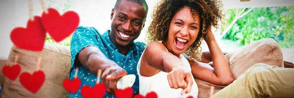 Corações Pendurados Uma Linha Contra Jovem Casal Feliz Assistindo Televisão — Fotografia de Stock