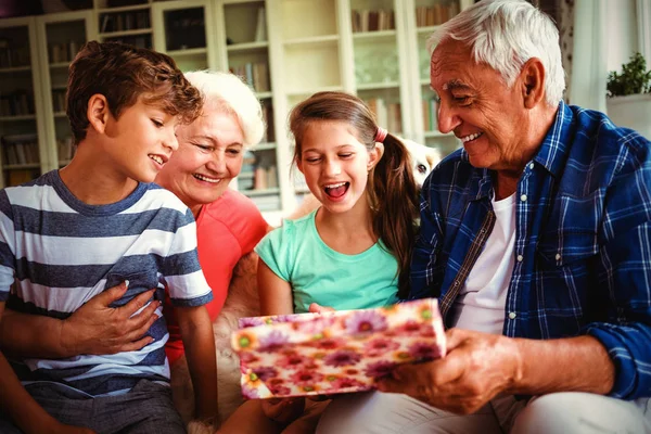 Großeltern Und Enkel Betrachten Überraschungsgeschenk Heimischen Wohnzimmer — Stockfoto