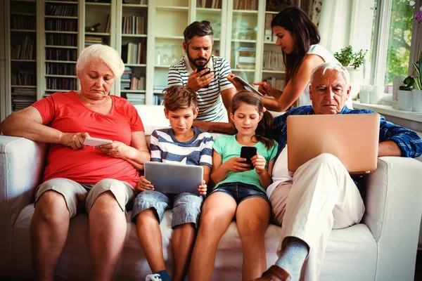 Mehrgenerationenfamilie Sitzt Auf Sofa Und Nutzt Hause Verschiedene Technologien — Stockfoto