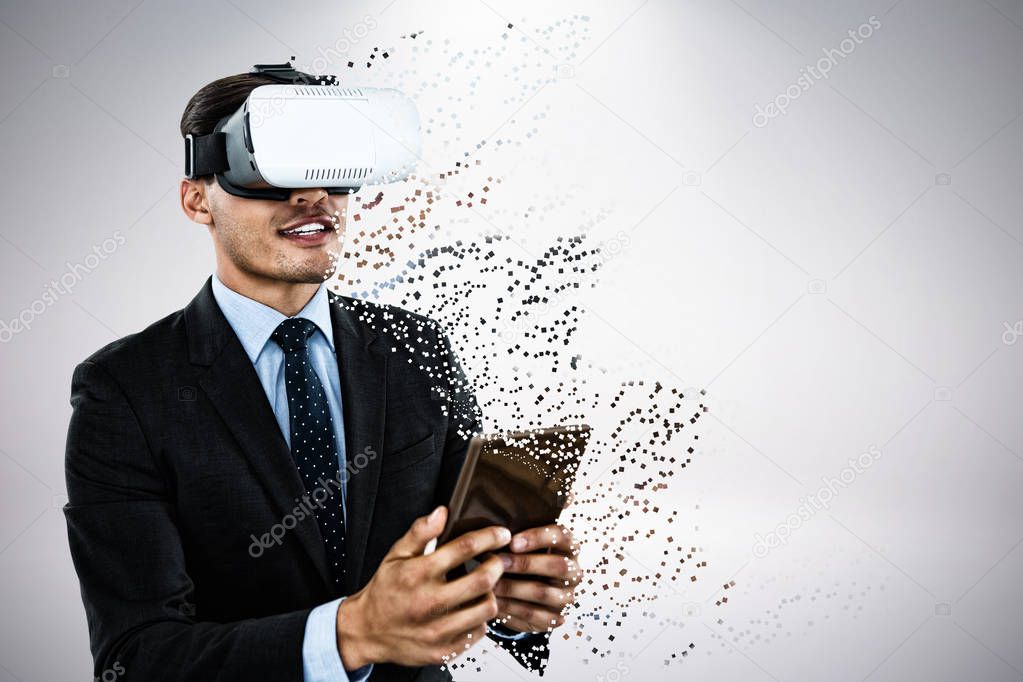 Businessman wearing vr glasses while using tablet against grey background