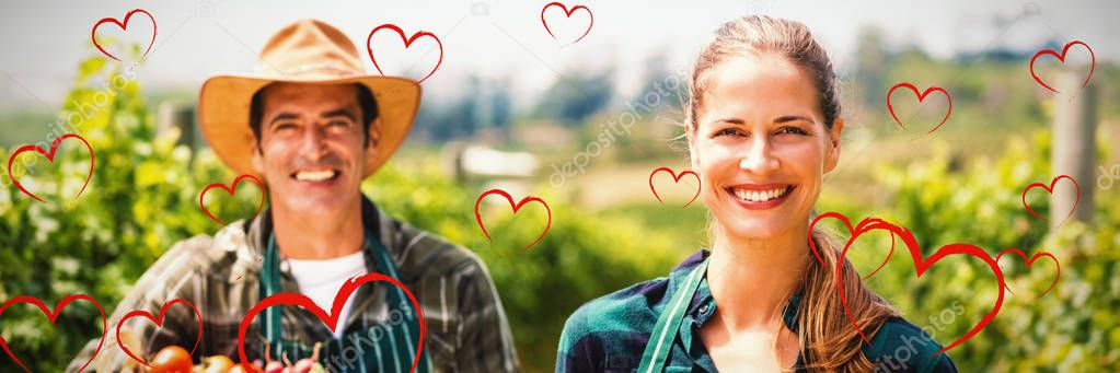 Red Hearts against portrait of happy farmer couple holding baskets of vegetables and fruits