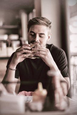Restoranda hamburger yiyen adam.