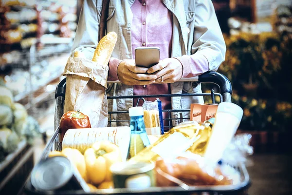 Seção Média Mulher Usando Telefone Celular Enquanto Faz Compras Supermercado — Fotografia de Stock