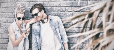 Cep telefonu kullaranarak duvara yaslanmış genç Çift