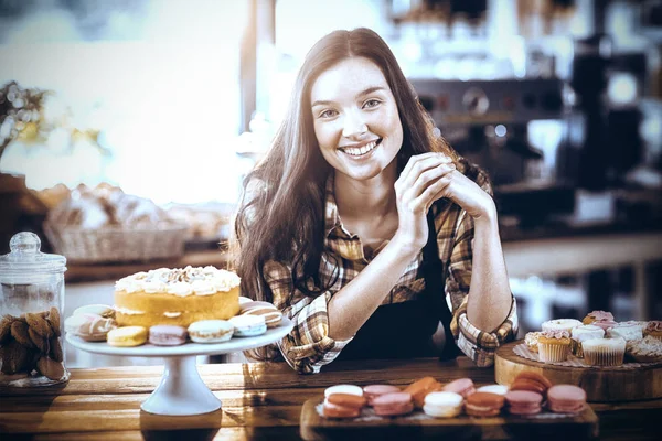 Portrait of waitress standing at counter with desserts in cafe
