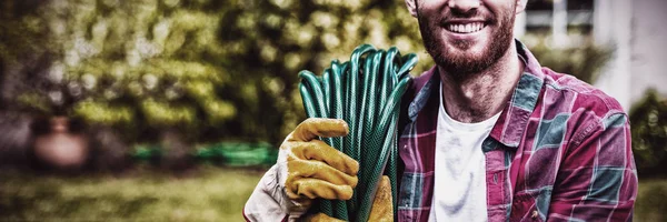 Glimlachende Man Met Tuinslang Terwijl Hij Achtertuin Staat — Stockfoto