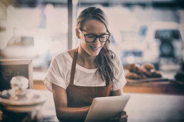 Masada oturan ve dijital tablet kullanarak kafede garson gülümseyerek