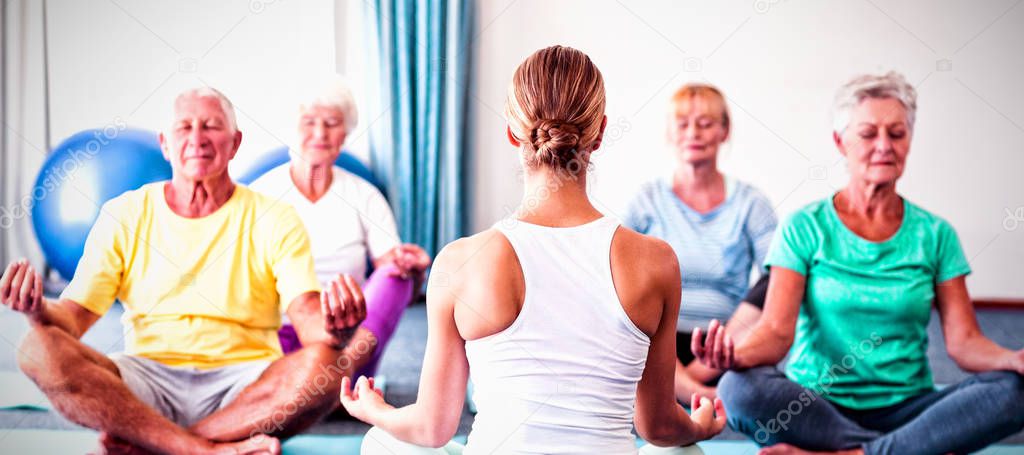 Instructor performing yoga with seniors during sports class