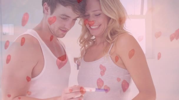数字复合的幸福夫妇看怀孕测试在卧室与飞行的心脏动画在前景 — 图库视频影像
