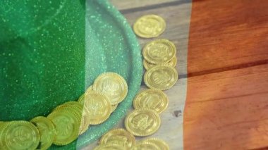 Altın ve yeşil şapka St Patrick's Day için ön plan üzerinde sallayarak İrlanda bayrağı ile ahşap masanın üzerine yerleştirilen dijital bileşik