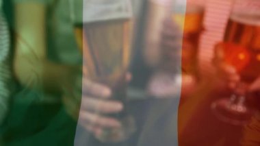 Farklı arkadaş bira bir pub ve St Patrick's Day için ön plan üzerinde sallayarak İrlanda bayrağı toasting dijital bileşik