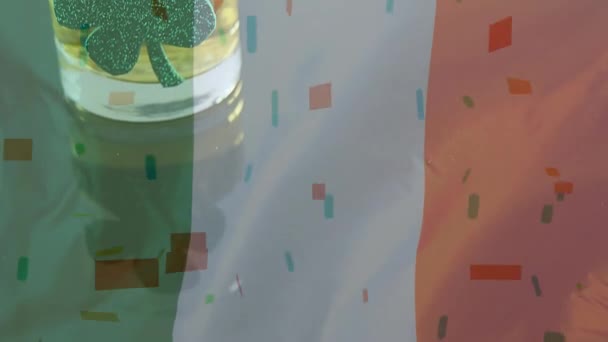 カラフルな紙吹雪が聖パトリックの日の手前に落ちるとアニメーションのアイルランドの旗背景にシャムロックとウイスキー グラスのデジタル合成 — ストック動画