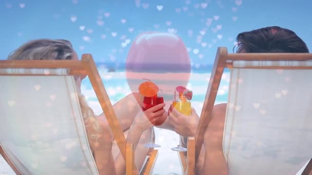 一对快乐的白种人坐在海边的椅子上 拿着粉红色的小心脏 喝着鸡尾酒 这种数字合成 — 图库视频影像