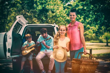 Piknik sepeti baba ve oğul Park'ta arka planda gitar çalmak süre ile anne ve kızı ayakta portresi