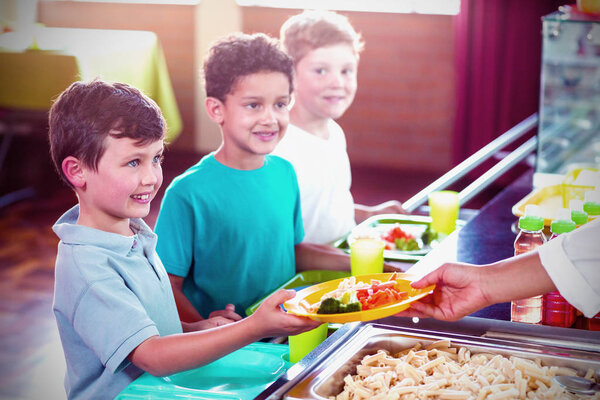 Cropped image of woman serving food to smiling schoolchildren in canteen