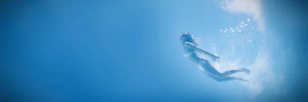 プール内の水の下で泳いでいるフィット女性 — ストック写真