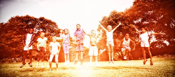 Niños Sonrientes Saltando Juntos Durante Día Soleado Parque — Foto de Stock