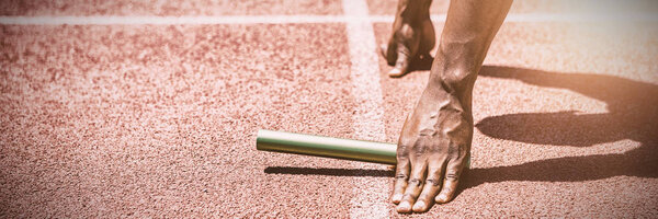 Hands of athlete holding baton on running track