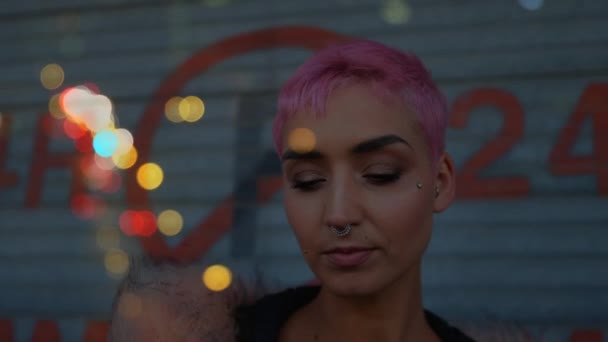携帯電話を使ってピンク色の髪の女性のデジタル複合体は ボケの効果に囲まれた通りに立っている — ストック動画