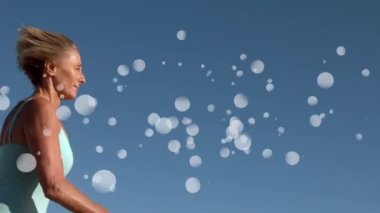 Mavi gökyüzüne karşı beyaz kabarcıklar etkisi ile çevrili çalışan olgun Kafkas kadının dijital kompozit