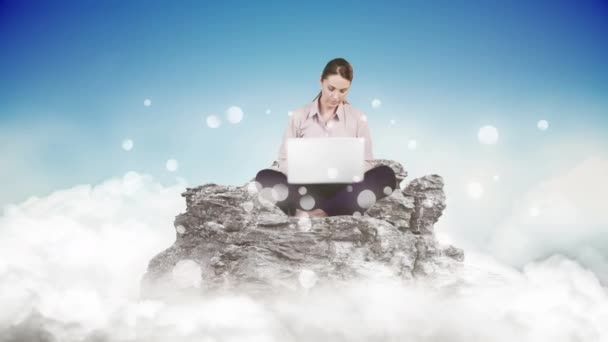 白い泡の影響に囲まれた岩の上に座っている彼女のラップトップを使用して白人女性のデジタル複合体曇りの空に対して — ストック動画