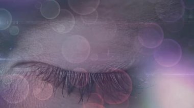 Bir küre ve dairesel bokeh ışıkları oluşturan asimetrik çizgiler odaklanırken yetişkin bir kadın gözü dijital kompozit.
