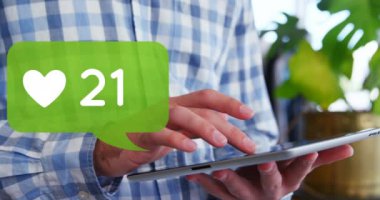 Kafkasyalı bir adamın kalp ikonuyla tabletine bakması ve ön plandaki yeşil sohbet kutusunda rakamların artması.