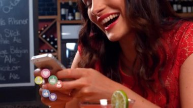 Bir barın önünde otururken telefonuna gülen beyaz bir kadının yakını. Gibi dijital animasyon, takip ve kalp simgeleri onun telefonyukarı uçuyor