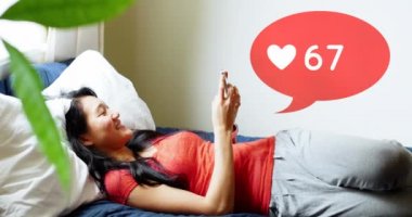 Telefonunda gezinirken yatakta gülümseyen Asyalı bir kadının yan görünümü. Ön planda onun üstünde bir kalp simgesi sayısı 4k artan bir mesaj balonu dijital animasyon