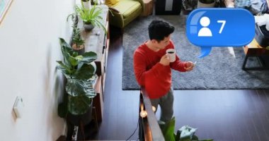 Beyaz bir adamın oturma odasında telefonuyla mesaj atarken kahve içerken yüksek açı. Ön planda onun üzerinde bir takipçisi simgesi sayısı artan bir mesaj balonu bir dijital animasyon. 4k