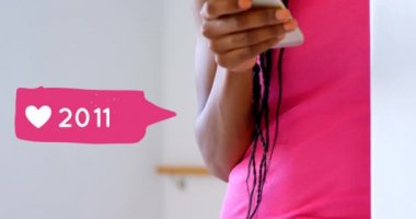 Telefonuna yazarken duvara yaslanmış Afro-Amerikalı bir kadının yakını. Ön planda onun yanında bir kalp simgesi sayısı 4k artan bir mesaj balonu dijital animasyon