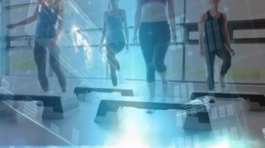 Spor salonunda egzersiz yapmayan bir grup kadının düşük açısı. Haritalar, istatistikler ve grafikleriçeren ekranların dijital animasyonu ön planda