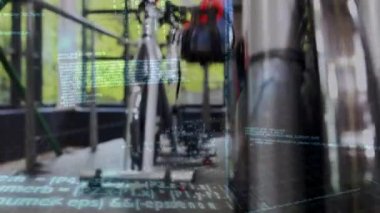 Spor salonunda sabit bir bisikletle egzersiz yapmakta olan beyaz bir kadının yakını. Program kodlarının dijital animasyonu arka planda çalışıyor